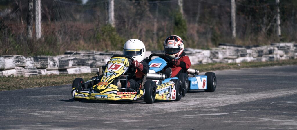 Two go-karts racing fiercely on an outdoor track showcasing speed and competition.