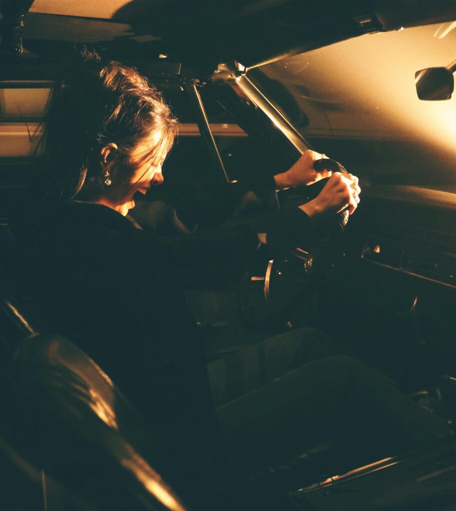 A woman enjoying the night drive experience in a warmly lit classic car interior, NJ.