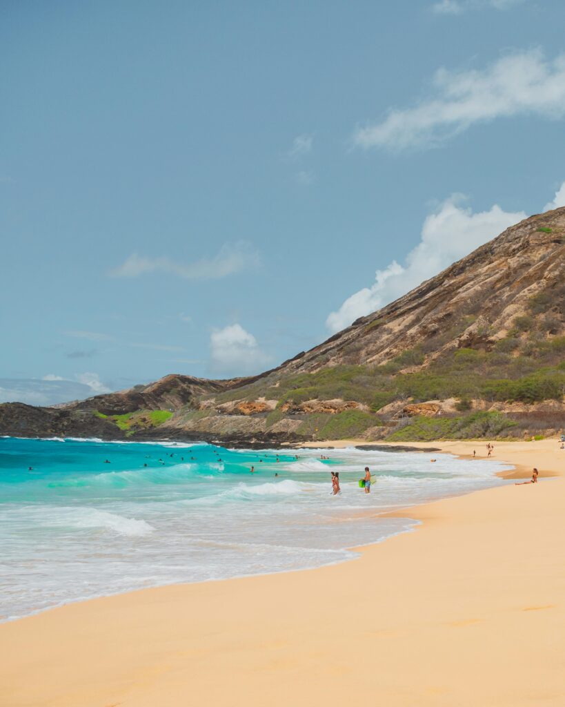 Idyllic beach scene featuring turquoise waters, golden sand, and distant swimmers enjoying a sunny day.